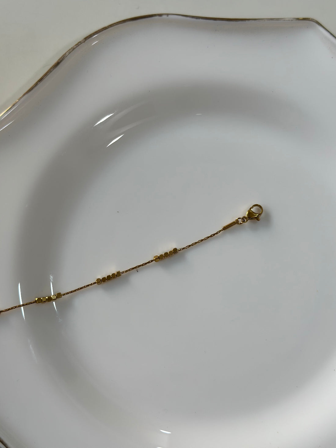 Gold bracelet on a white plate