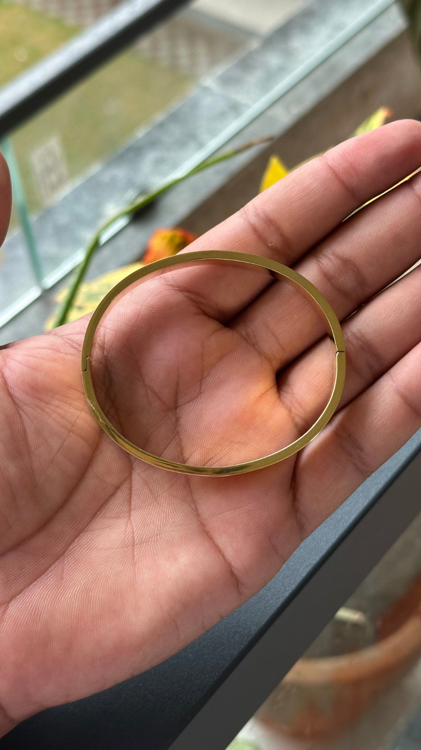 Gold ring held in a hand with a blurred outdoor background