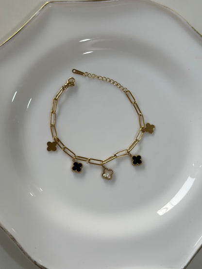 Gold bracelet with charms on a white plate