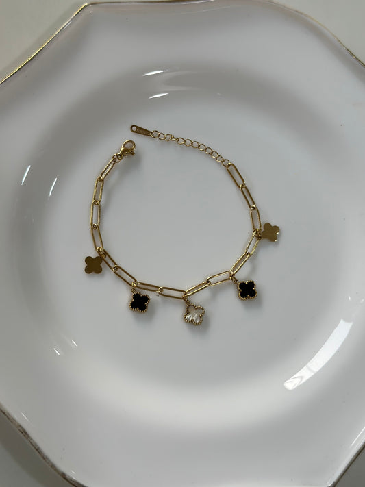 Gold bracelet with charms on a white plate