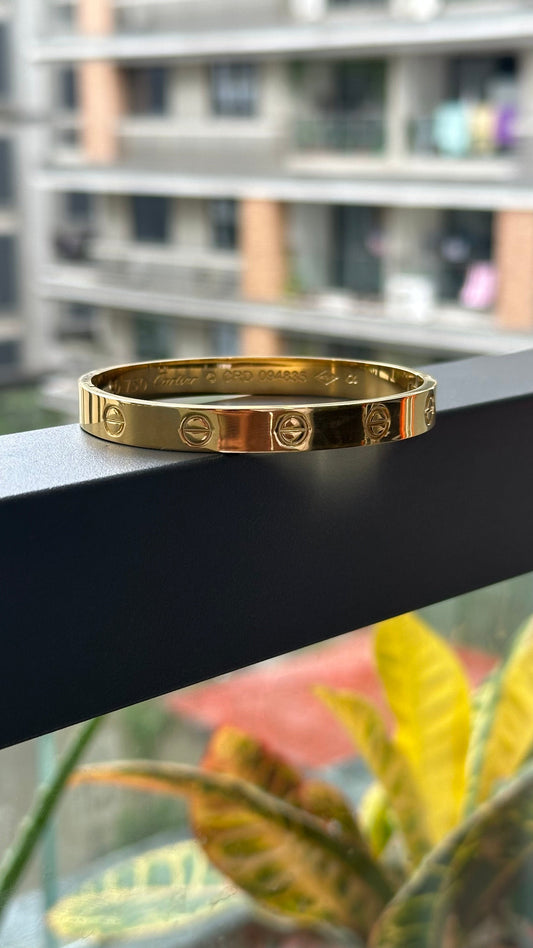 Gold bracelet on a black surface with blurred background