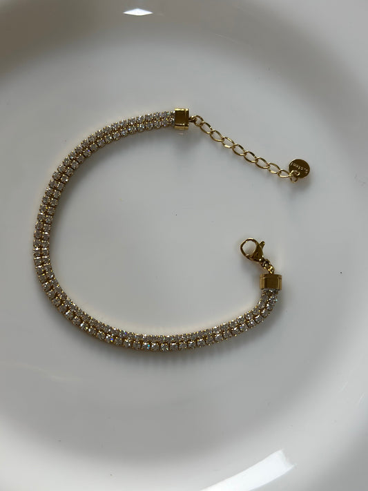 Gold bracelet with clear stones on a white background